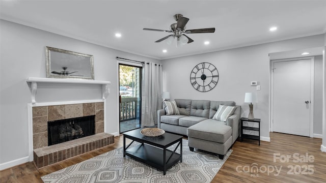 living room featuring hardwood / wood-style flooring, a tile fireplace, and ceiling fan