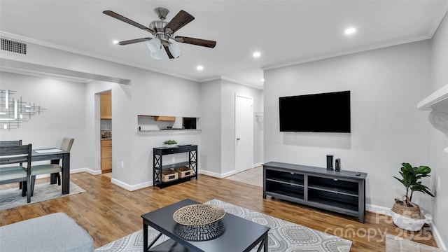 living room featuring ceiling fan, light wood-type flooring, and crown molding