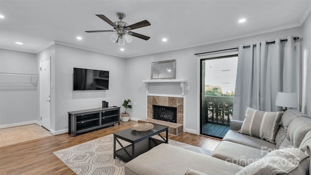 living room with ceiling fan, wood-type flooring, a fireplace, and crown molding