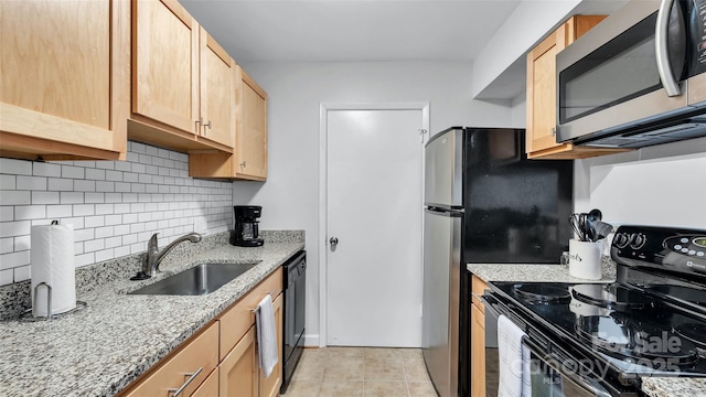 kitchen with light brown cabinets, tasteful backsplash, black appliances, light stone counters, and sink