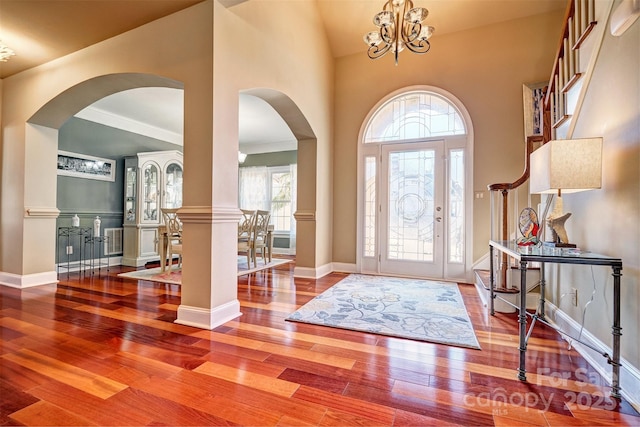 foyer with an inviting chandelier, high vaulted ceiling, a healthy amount of sunlight, and hardwood / wood-style floors