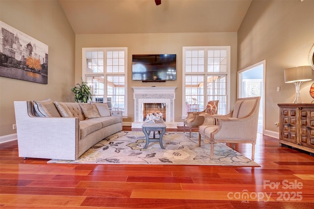 living room with a brick fireplace, plenty of natural light, hardwood / wood-style floors, and high vaulted ceiling