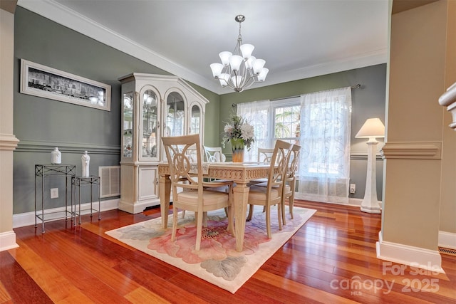 dining space featuring ornamental molding, a chandelier, and wood-type flooring