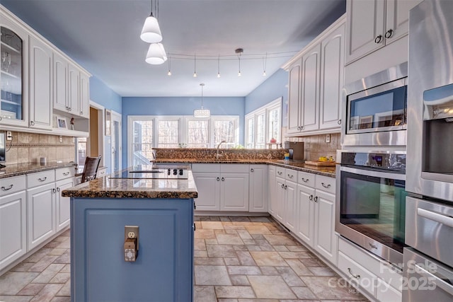 kitchen featuring decorative backsplash, stainless steel appliances, white cabinets, and a kitchen island