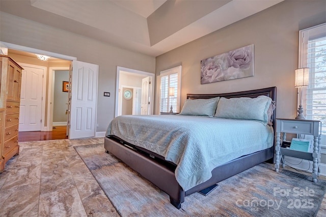 bedroom featuring multiple windows and a raised ceiling