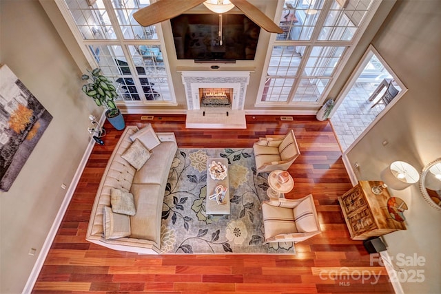 living room with a towering ceiling, a tiled fireplace, and hardwood / wood-style floors