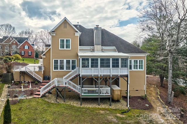 back of property with a wooden deck, a sunroom, and a lawn