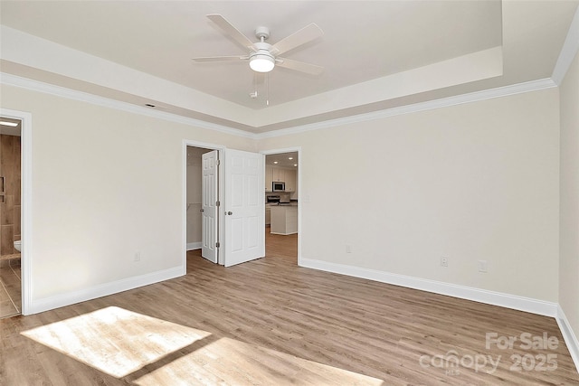 unfurnished bedroom featuring ceiling fan, connected bathroom, light hardwood / wood-style flooring, and a tray ceiling