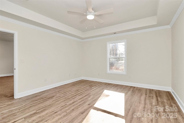 unfurnished room with light wood-type flooring, ceiling fan, ornamental molding, and a tray ceiling