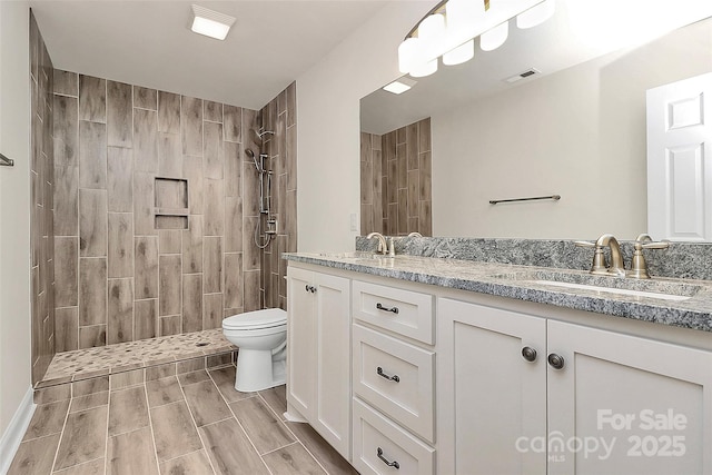 bathroom with toilet, vanity, and tiled shower