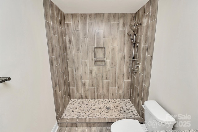 bathroom with toilet and a tile shower