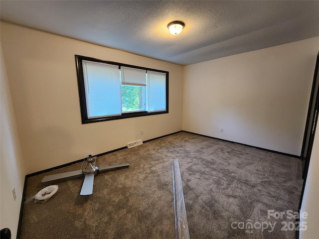 carpeted spare room featuring a textured ceiling