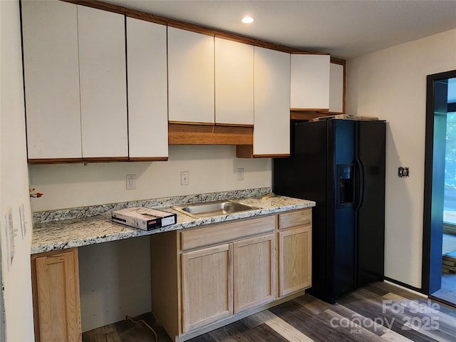 kitchen with dark hardwood / wood-style flooring, sink, light stone counters, and black fridge