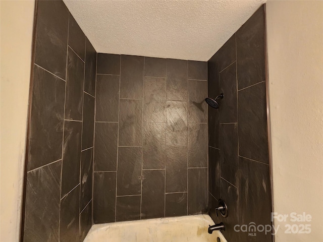 bathroom with tiled shower / bath combo and a textured ceiling