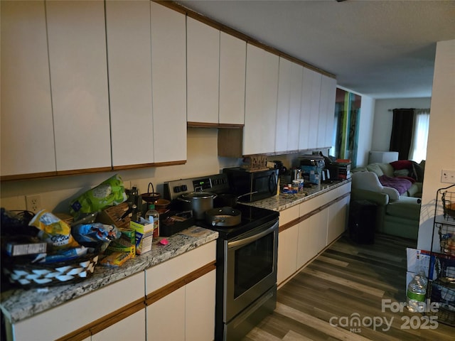 kitchen with dark hardwood / wood-style flooring, electric range, light stone countertops, and white cabinets