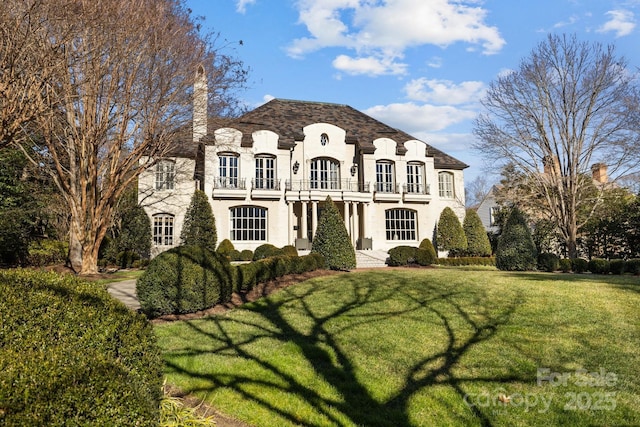 french country home with a balcony and a front lawn