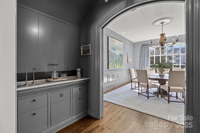 interior space featuring light wood-type flooring, hanging light fixtures, a notable chandelier, and gray cabinetry