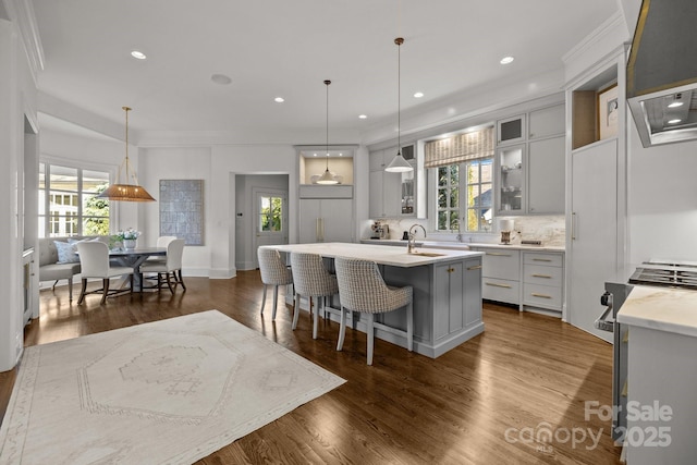 kitchen with pendant lighting, a breakfast bar, a wealth of natural light, and an island with sink