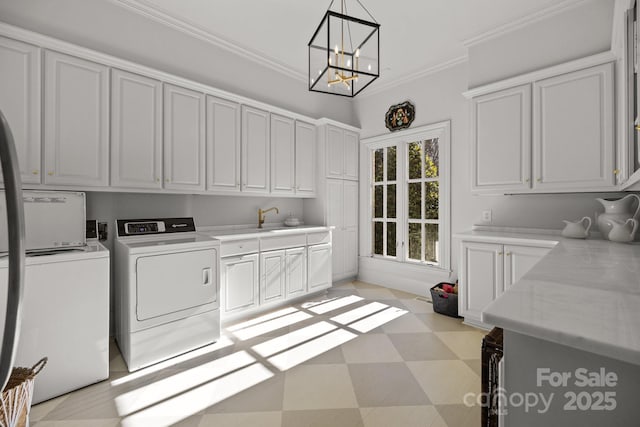 laundry area with a notable chandelier, sink, ornamental molding, washing machine and dryer, and cabinets