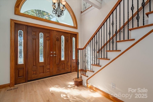 entryway featuring a towering ceiling, hardwood / wood-style floors, and a notable chandelier