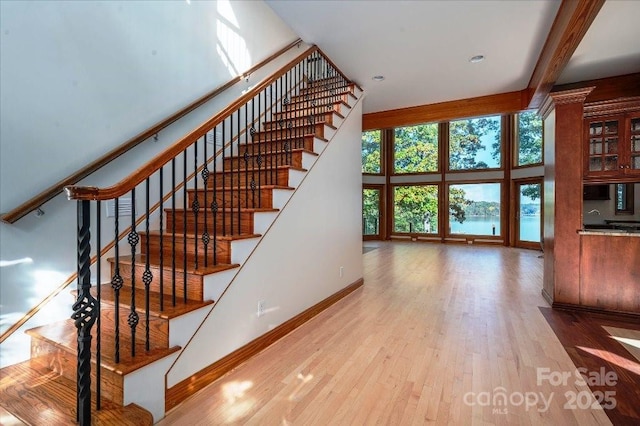 stairway featuring wood-type flooring, floor to ceiling windows, and a high ceiling