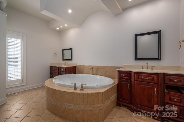 bathroom with a relaxing tiled tub, vanity, and tile patterned flooring