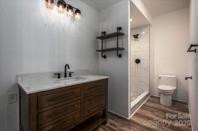 bathroom featuring vanity, wood-type flooring, a tile shower, and toilet