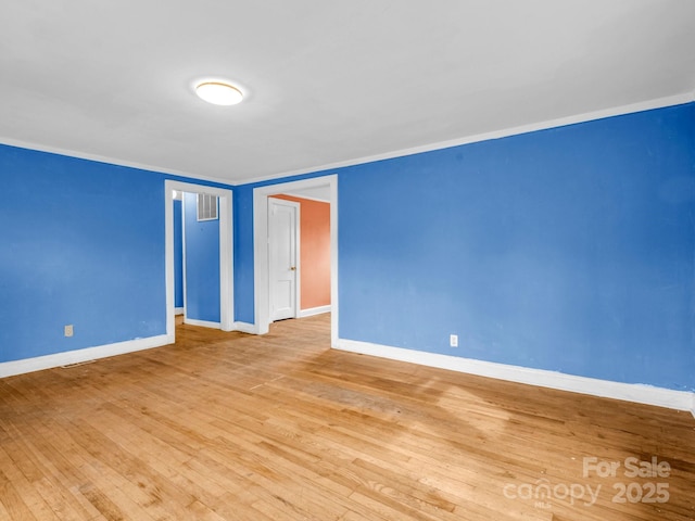 spare room with ornamental molding and light hardwood / wood-style floors