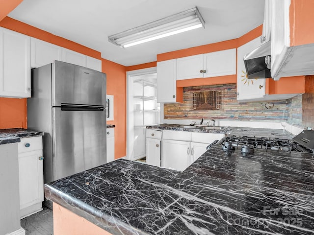 kitchen featuring stainless steel refrigerator, white cabinetry, and decorative backsplash