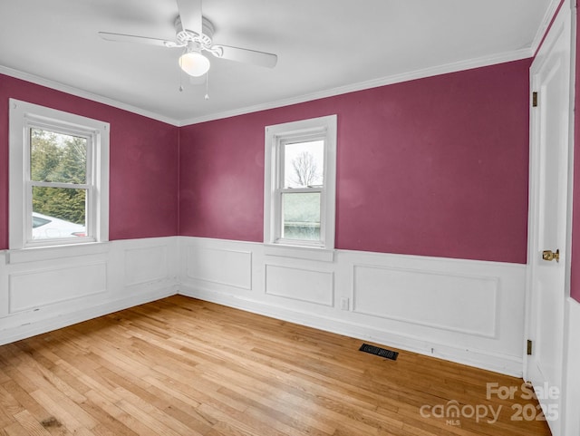 spare room featuring ceiling fan, a healthy amount of sunlight, hardwood / wood-style floors, and ornamental molding