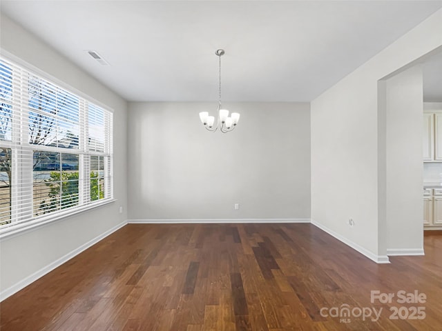 unfurnished room with a chandelier and dark hardwood / wood-style floors