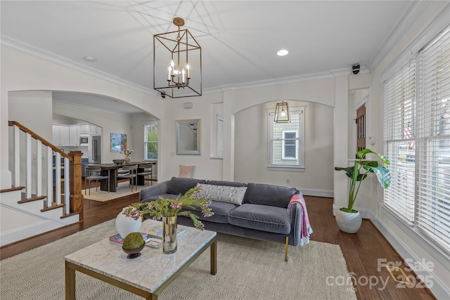 living room featuring crown molding, wood-type flooring, and an inviting chandelier