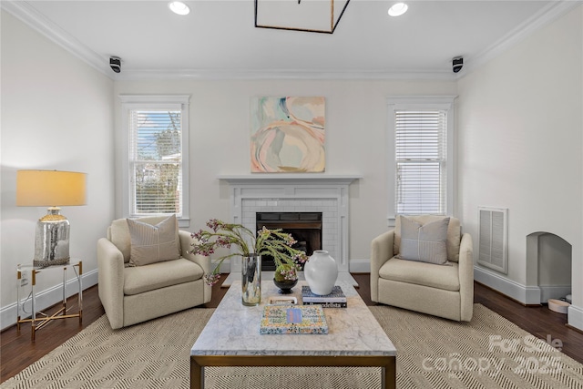 living area with a brick fireplace, crown molding, and hardwood / wood-style floors