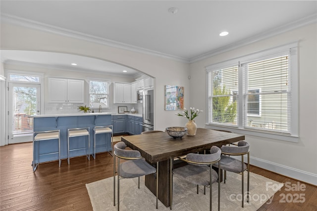 dining space with sink, ornamental molding, and light hardwood / wood-style floors