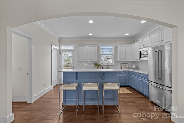 kitchen featuring appliances with stainless steel finishes, white cabinets, backsplash, ornamental molding, and blue cabinetry