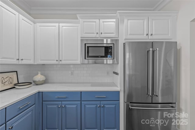 kitchen with blue cabinetry, appliances with stainless steel finishes, tasteful backsplash, ornamental molding, and white cabinets