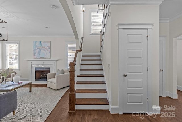 staircase featuring a tiled fireplace, crown molding, and hardwood / wood-style floors