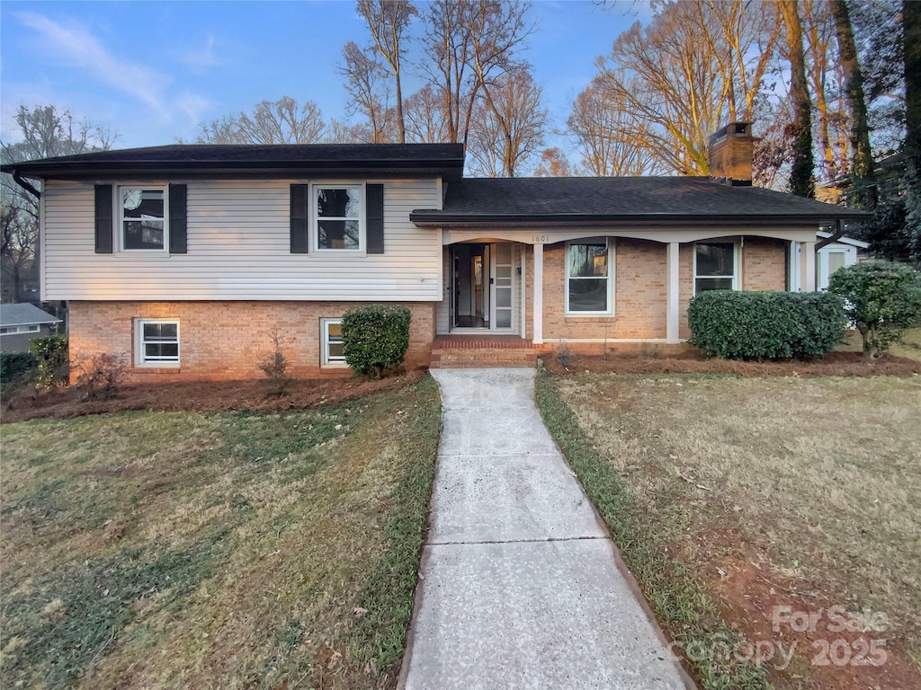 split level home with covered porch and a front yard