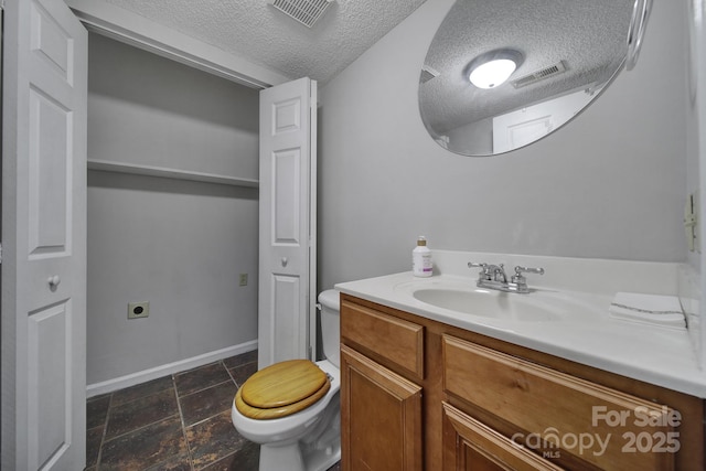 bathroom featuring toilet, a textured ceiling, and vanity