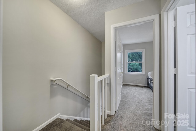 hallway featuring a textured ceiling and light carpet