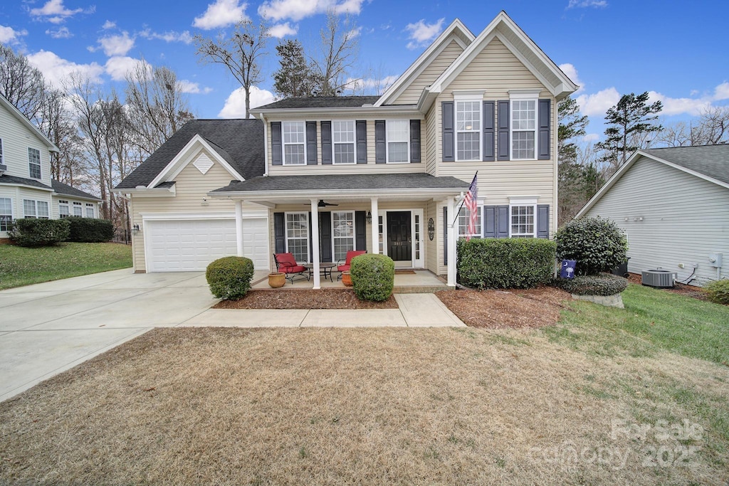 view of property featuring central AC unit, a garage, a front yard, and a porch