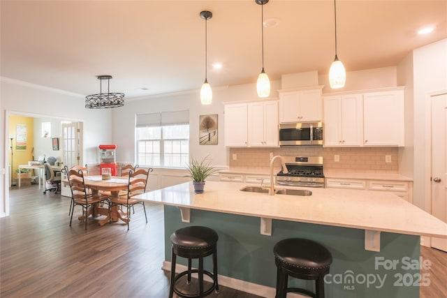 kitchen with decorative light fixtures, sink, white cabinetry, and appliances with stainless steel finishes