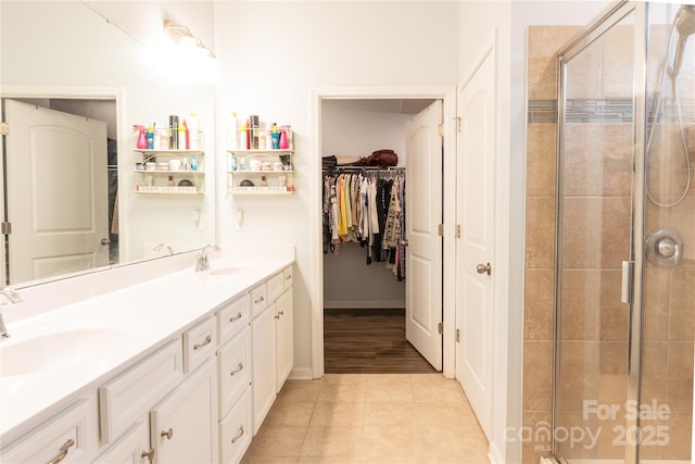 bathroom with a shower with shower door, vanity, and tile patterned flooring