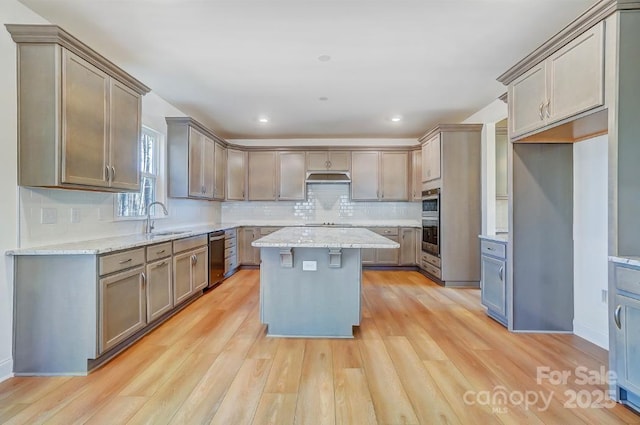 kitchen featuring light stone counters, sink, a center island, and light hardwood / wood-style flooring