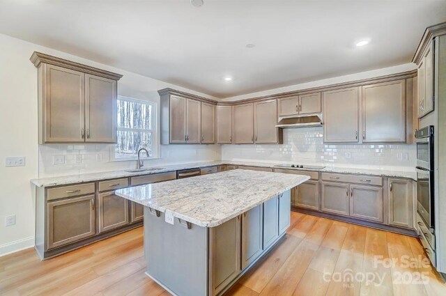 kitchen with light stone counters, sink, light hardwood / wood-style flooring, and black electric cooktop