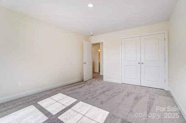 unfurnished bedroom featuring a closet and light carpet