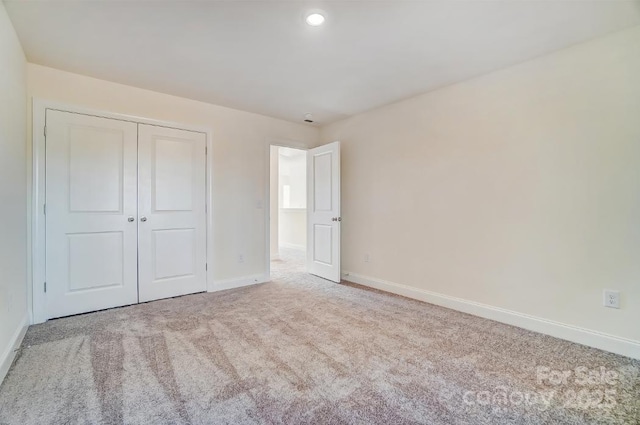 unfurnished bedroom with light carpet and a closet