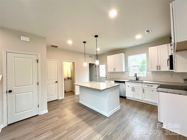 kitchen with white cabinetry, dishwasher, hanging light fixtures, light stone countertops, and a center island