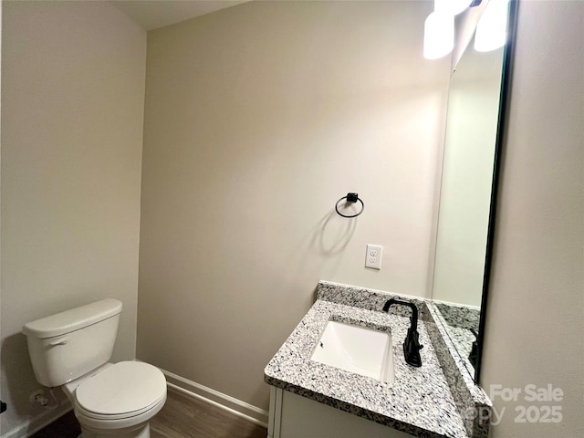 bathroom featuring wood-type flooring, toilet, and vanity