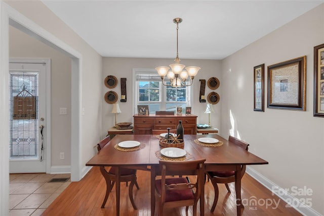 dining room with light tile patterned floors and an inviting chandelier